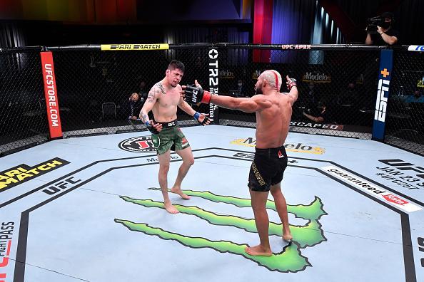 Brandon Moreno and Deiveson Figueiredo embrace in the cage at UFC 256. Credit to: Zuffa LLC.