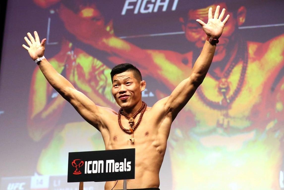 Li Jingliang absorbs the energy of the crowd on top the scale. Credits to: AP Photo/Gregory Payan