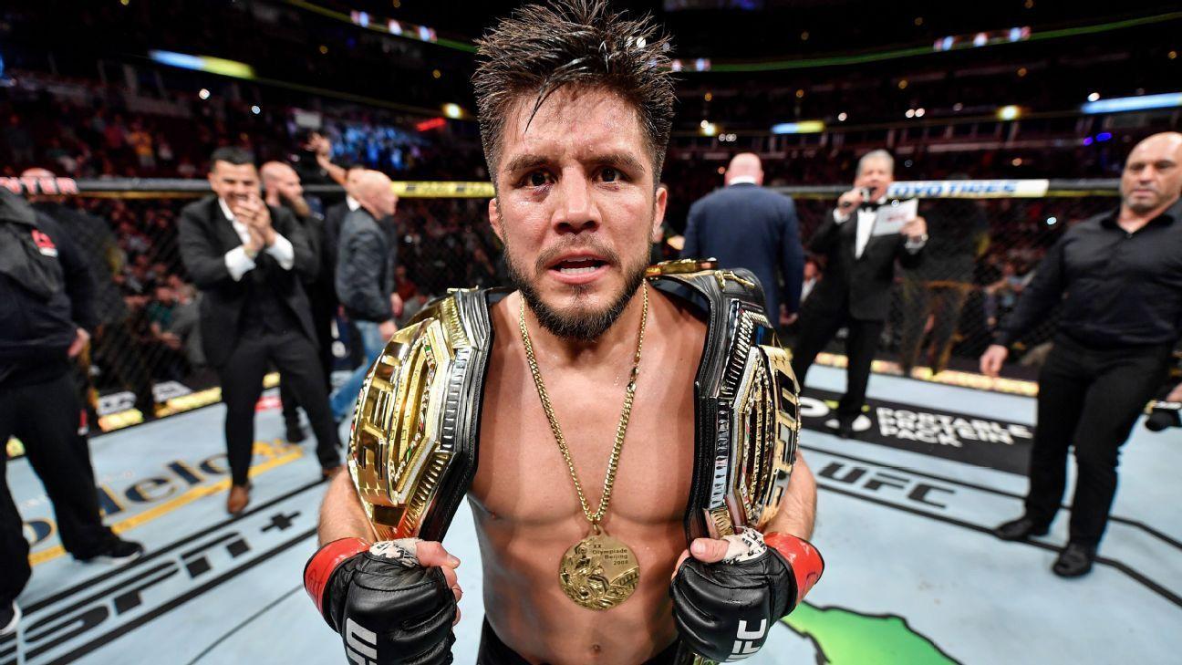 Henry Cejudo with his Olympic gold medal and two UFC titles. Credits to: Zuffa LLC.